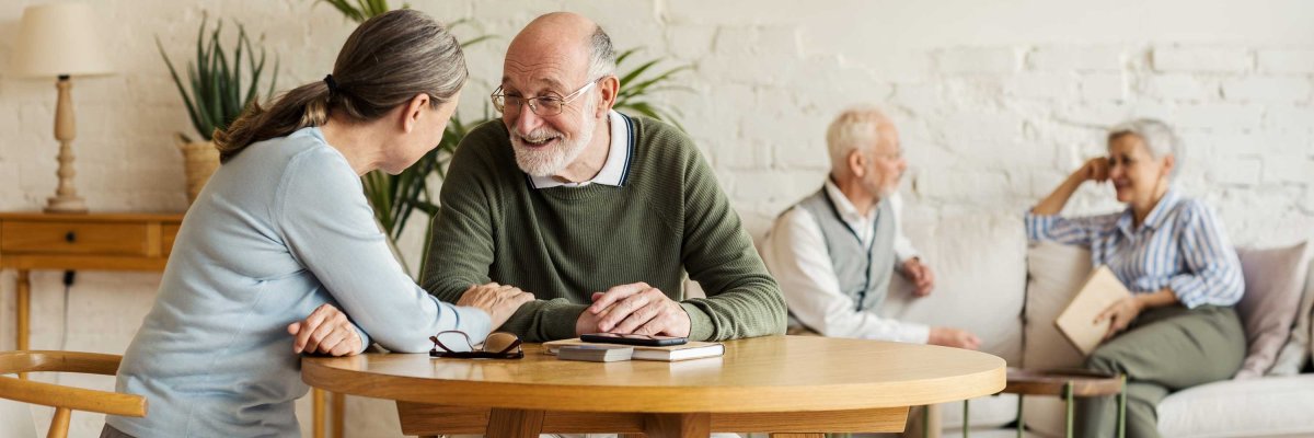 Elderly,Man,And,Woman,Sitting,At,Table,And,Enjoying,Joyful