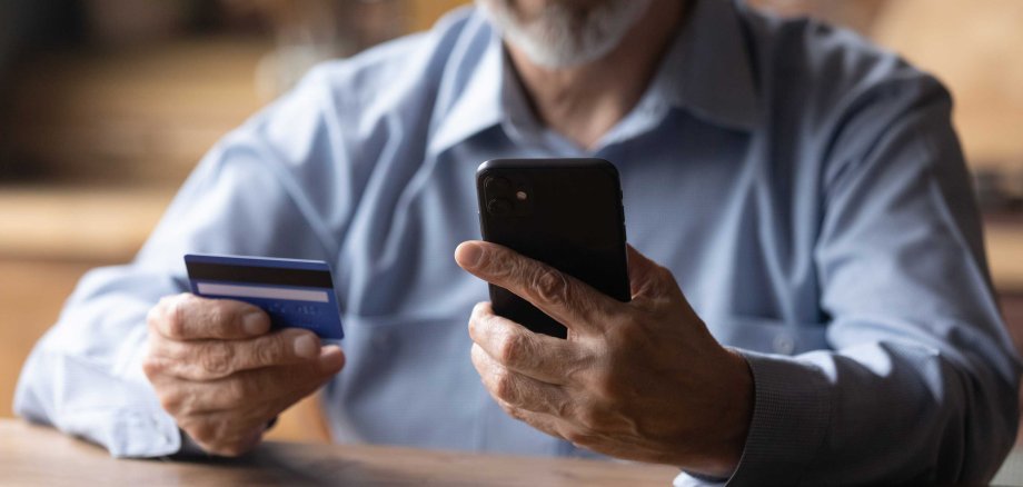 Close,Up,Mature,Man,Using,Phone,,Holding,Plastic,Credit,Or