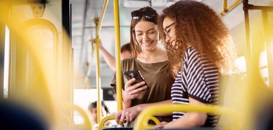 Two,Cheerful,Pretty,Young,Women,Are,Standing,In,A,Bus